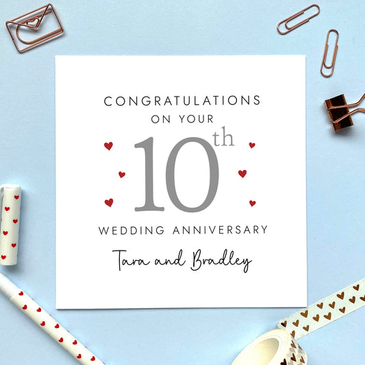 A personalised 10th wedding anniversary card for couple. It features '10th' in grey with red hearts, the colour scheme matches the theme of tin. The text reads 'Congratulations on your 10th wedding anniversary'. This card can be personalised with two names, and is suitable for special friends and family relations such as Daughter and Son-in-Law and Son and Daughter-in-Law. It is also suitable for gay and lesbian couples.