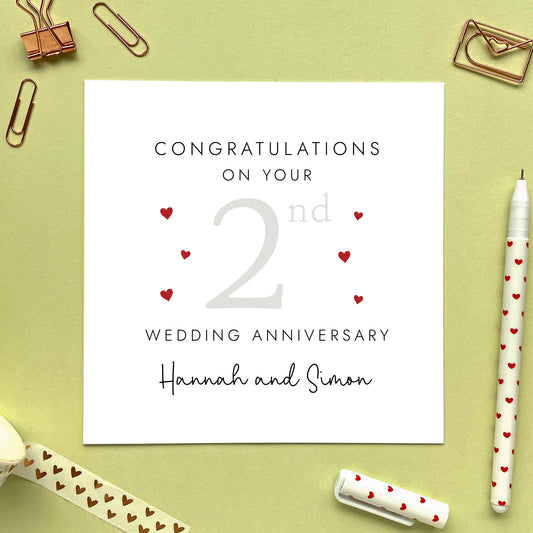 A personalised 2nd wedding anniversary card for couple. It features '2nd' in a pale grey with red hearts, the colour scheme matches the theme of cotton. The text reads 'Congratulations on your 2nd wedding anniversary'. This card can be personalised with two names, and is suitable for special friends and family relations such as Daughter and Son-in-Law and Son and Daughter-in-Law. It is also suitable for gay and lesbian couples.