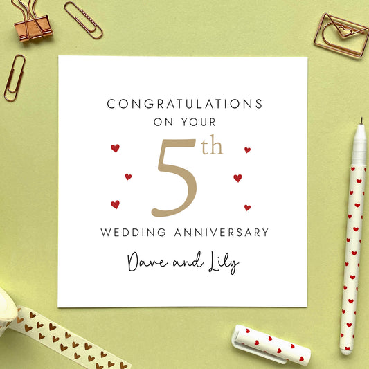 A personalised 5th wedding anniversary card for couple. It features '5th' in light brown with red hearts, the colour scheme matches the theme of wood. The text reads 'Congratulations on your 5th wedding anniversary'. This card can be personalised with two names, and is suitable for special friends and family relations such as Daughter and Son-in-Law and Son and Daughter-in-Law. It is also suitable for gay and lesbian couples.