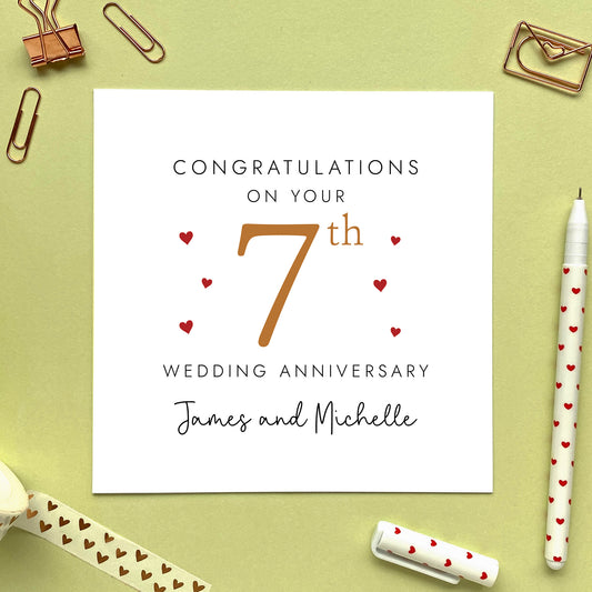 A personalised 7th wedding anniversary card for couple. It features '7th' in copper brown with red hearts, the colour scheme matches the theme of copper. The text reads 'Congratulations on your 7th wedding anniversary'. This card can be personalised with two names, and is suitable for special friends and family relations such as Daughter and Son-in-Law and Son and Daughter-in-Law. It is also suitable for gay and lesbian couples.