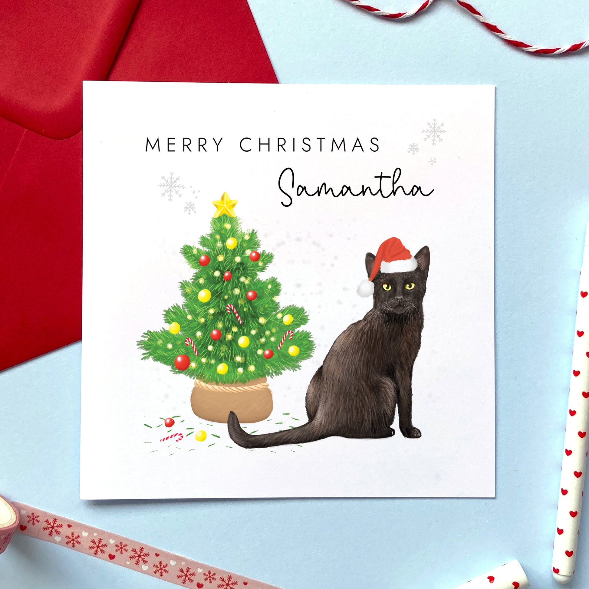 A personalised Christmas card featuring a black cat wearing a Santa hat sitting next to a Christmas tree. It can be personalised with any name. Ideal for both him and her. Suitable for a range of relations such as Daughter, Granddaughter, Mum, Sister, Friend and Auntie.