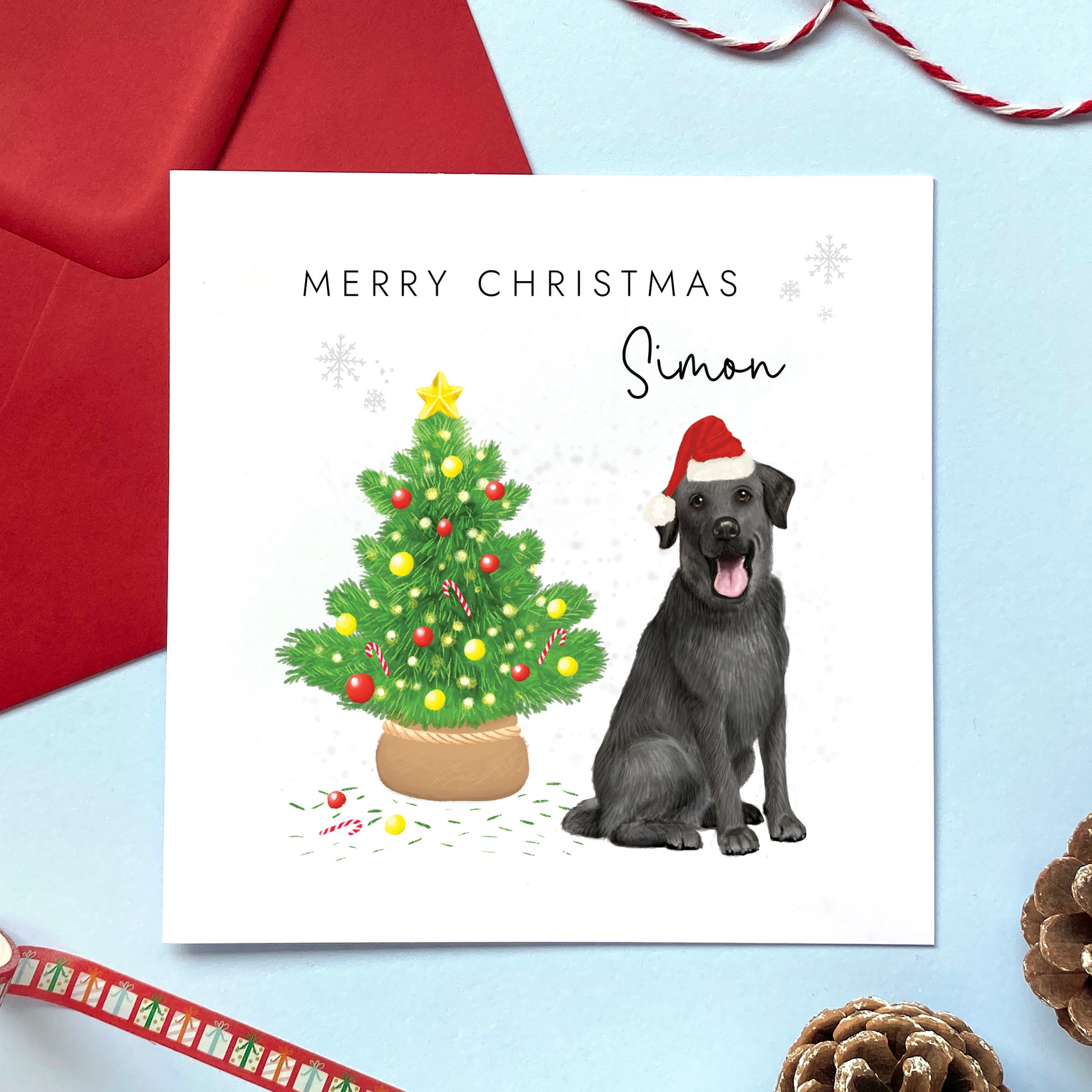 A personalised Christmas card featuring a black labrador dog wearing a santa hat next to a christmas tree. It can be personalised with a name, and is suitable for a range of relations such as Husband, Boyfriend, Wife, Brother, Son and Grandson.