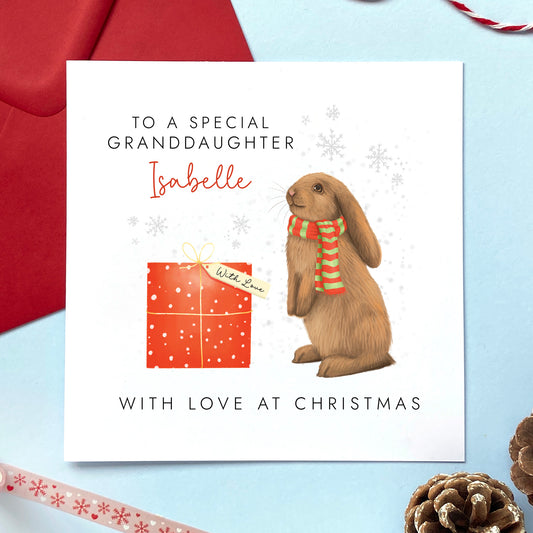 A personalised Christmas card for girl featuring a brown bunny rabbit and red present. The card in the photo is a Christmas card for Granddaughter.