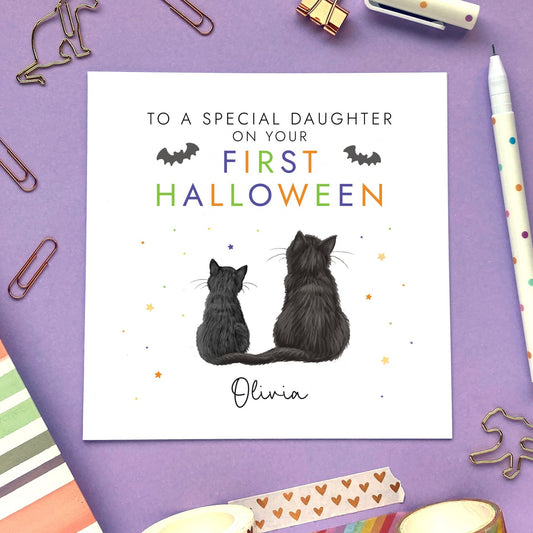 A personalised 1st Halloween Card for Baby's First Halloween. It can be personalised with a name and relation. Both cats on the card can be chosen. The card in the photo is a First Halloween Card for Daughter with Black Cats.