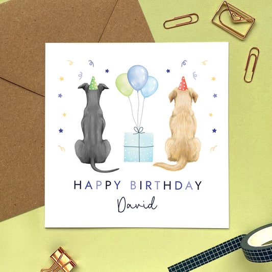 A personalised dog themed birthday card for him where you can choose the two dogs from different breeds. The card in the photo is a birthday card for him featuring a blue greyhound and a golden labrador.