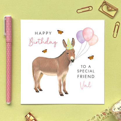 A personalised birthday card for her featuring a donkey with birthday balloons. It can be personalised with a name, relation and any age. The card in the photo is a birthday card for Friend.