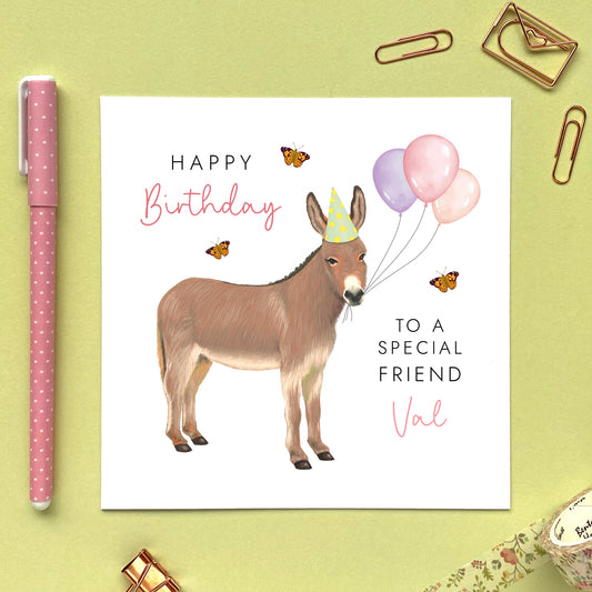 A personalised birthday card for her featuring a donkey with birthday balloons. It can be personalised with a name, relation and any age. The card in the photo is a birthday card for Friend.