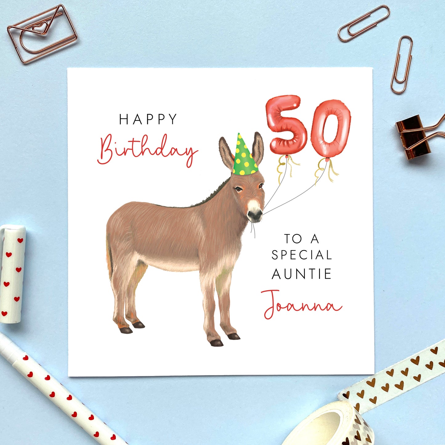 A personalised birthday card for her or him featuring a donkey with birthday balloons. It can be personalised with a name, relation and any age. The card in the photo is a 50th birthday card for Auntie.