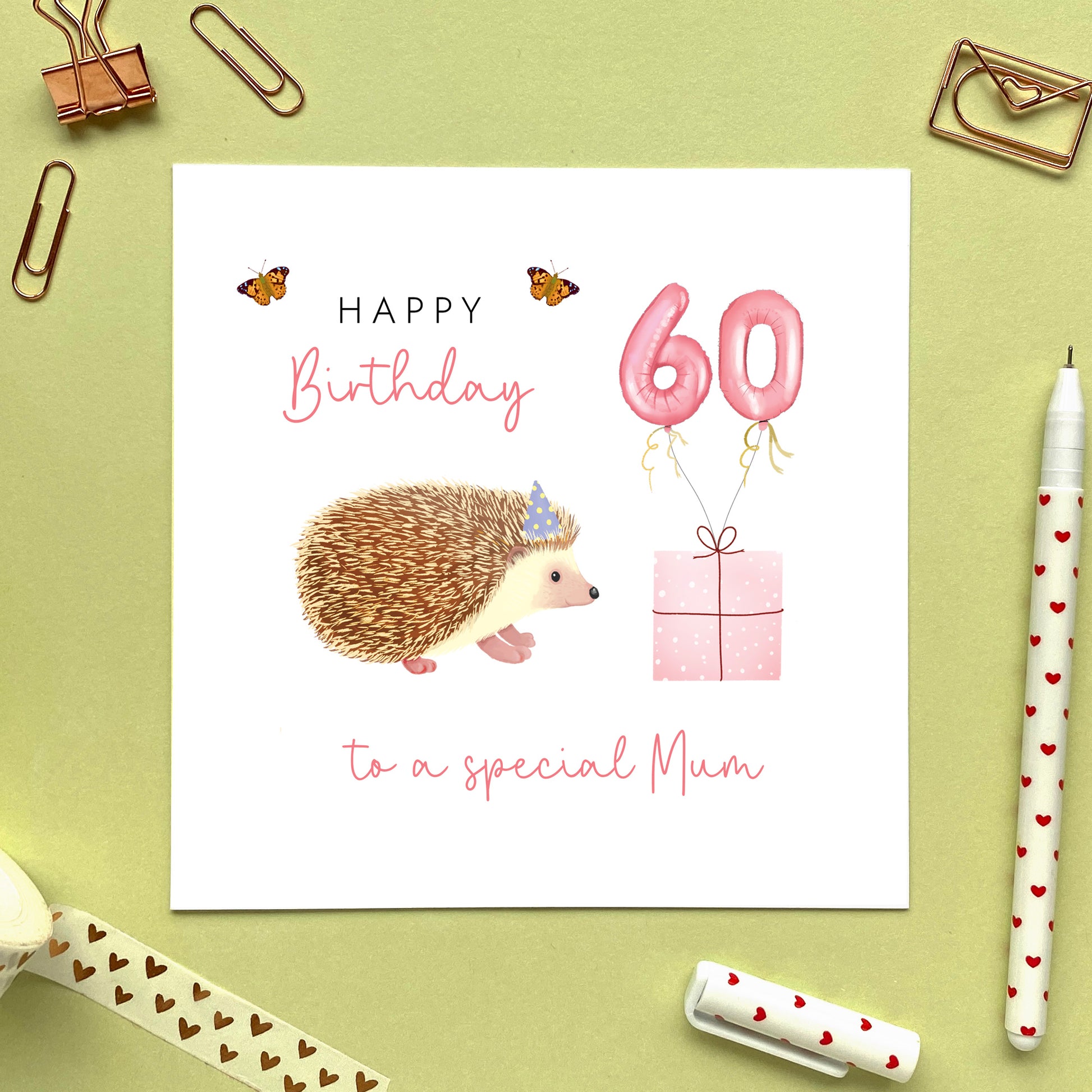 A personalised hedgehog birthday card for Her. It is pink and purple themed, and can be personalised with a name and any age. The card in the photo is a 60th birthday card for Mum.