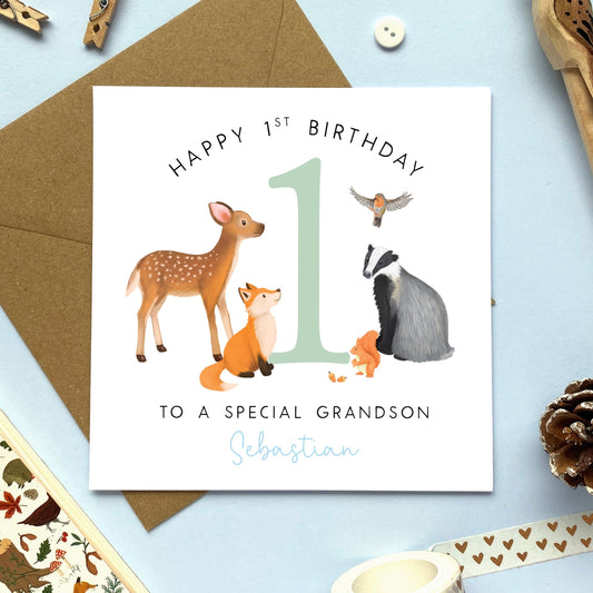 A personalised woodland animals 1st birthday card for boy. The design features the number one with a brown deer, fox, badger, red squirrel and robin. It's suitable for children and baby, including Son, Grandson, Nephew, Brother and Cousin. It can be personalised with any name. The card in the photo is a 1st birthday card for grandson.