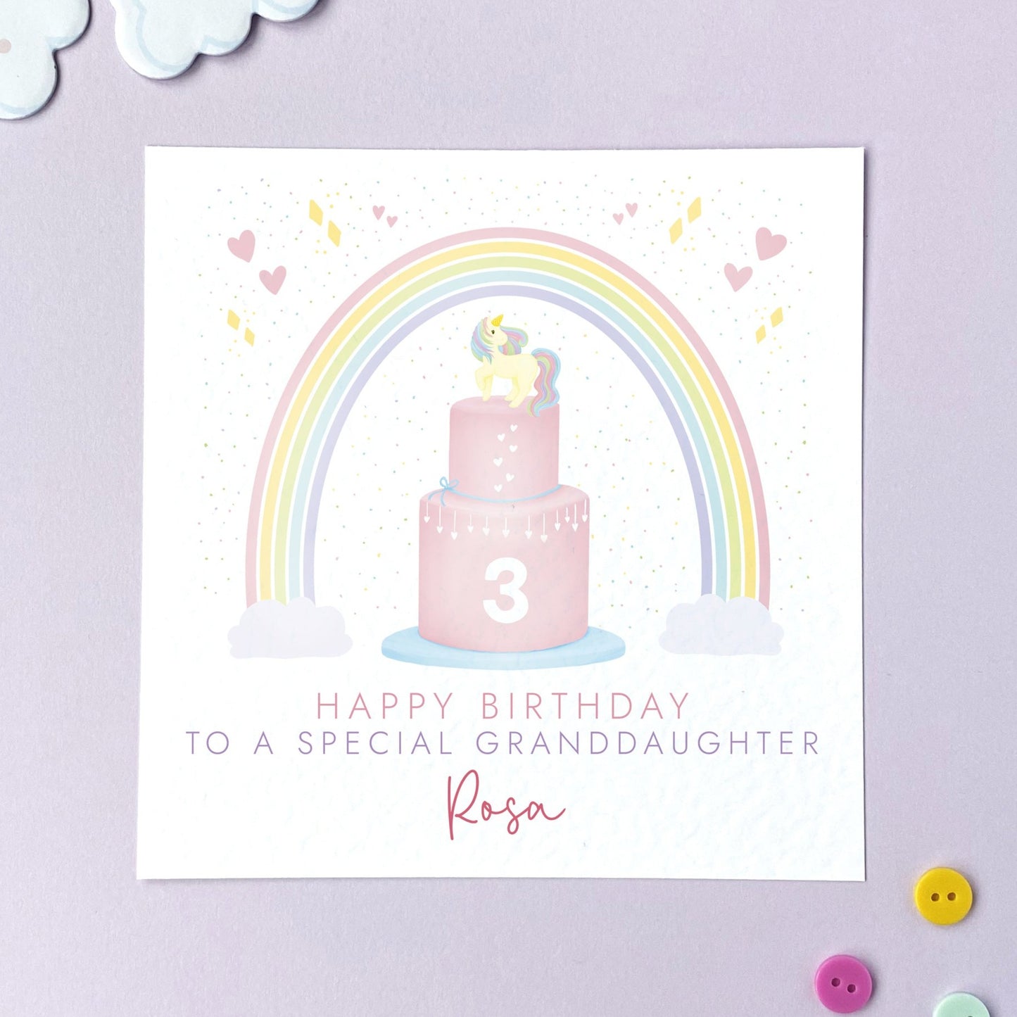 A personalised any age birthday card for girl featuring a unicorn themed birthday cake with pastel rainbow. It's ideal for female family relations or children, such as Daughter, Granddaughter, Niece, Sister, Cousin and Little Girl. It can be personalised with a name. The number can be changed to any age, such as 1st, 2nd, 3rd, 4th and 5th birthday. The card in the photo is a 3rd birthday card for granddaughter.